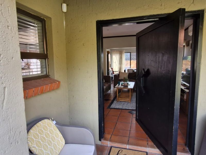 Entrance area featuring a solid security door, terracotta tiled flooring, and a window with blinds, providing access to the interior living space.
