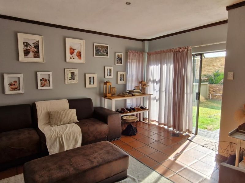 A living room featuring terracotta floor tiles and a sliding glass door providing direct access to the rear garden.