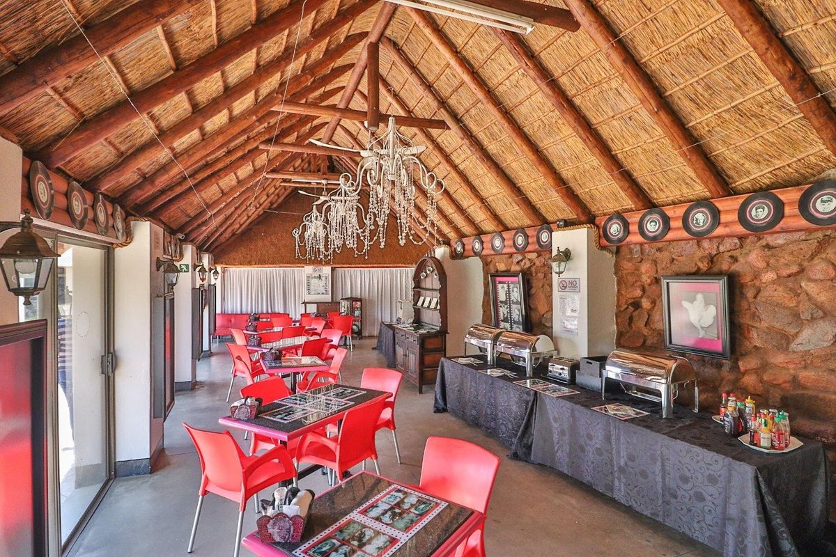 Spacious rustic living area featuring a high thatched roof with exposed timber trusses and distinctive stone wall cladding, offering a unique farm-style atmosphere.
