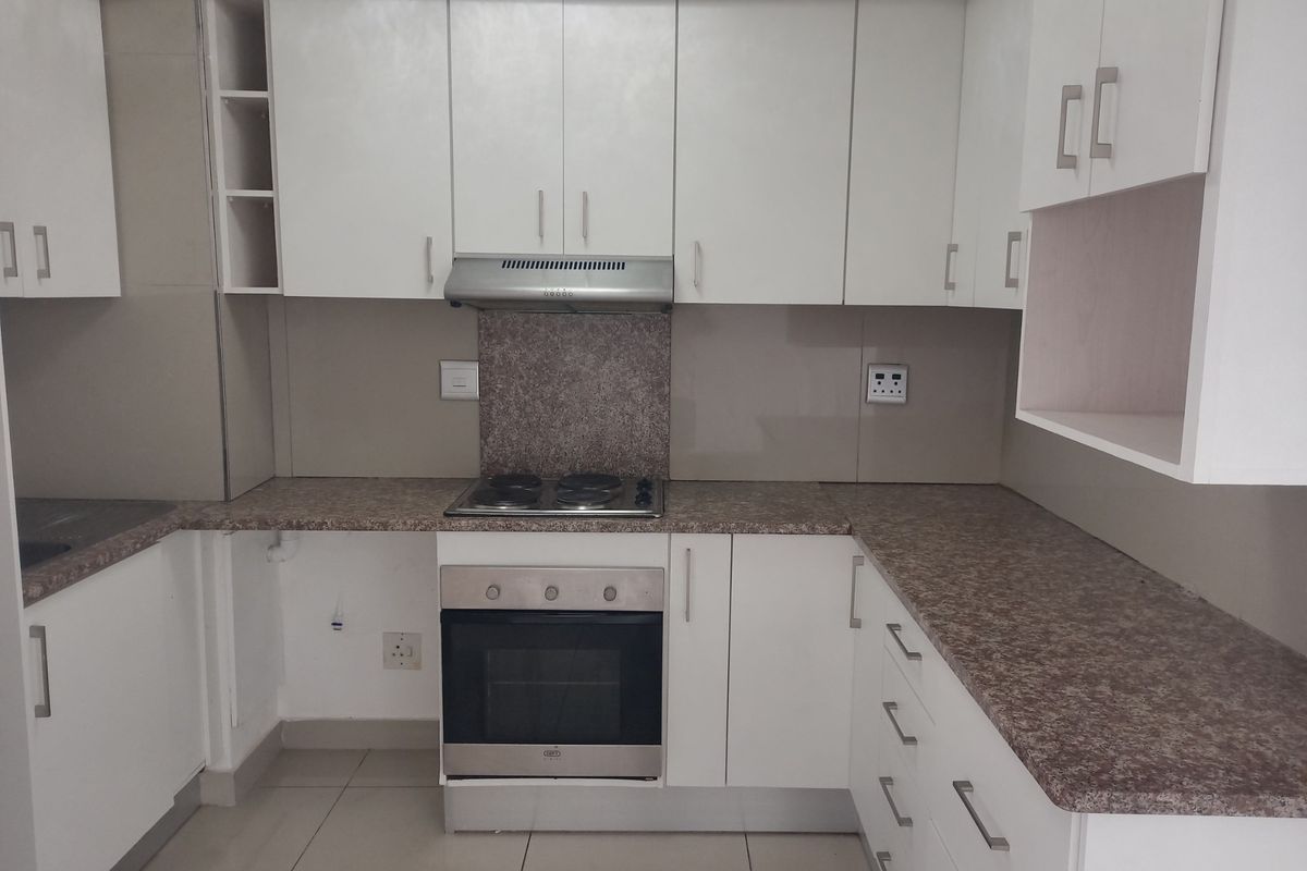 A functional kitchen featuring white cabinetry, laminate countertops, a built-in oven, and an electric hob, offering a clean and practical workspace.