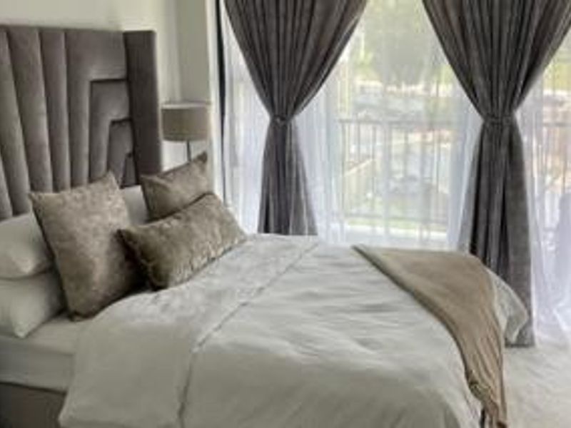 A well-lit bedroom featuring a large window and sliding door access to a private balcony, creating a bright and airy atmosphere.