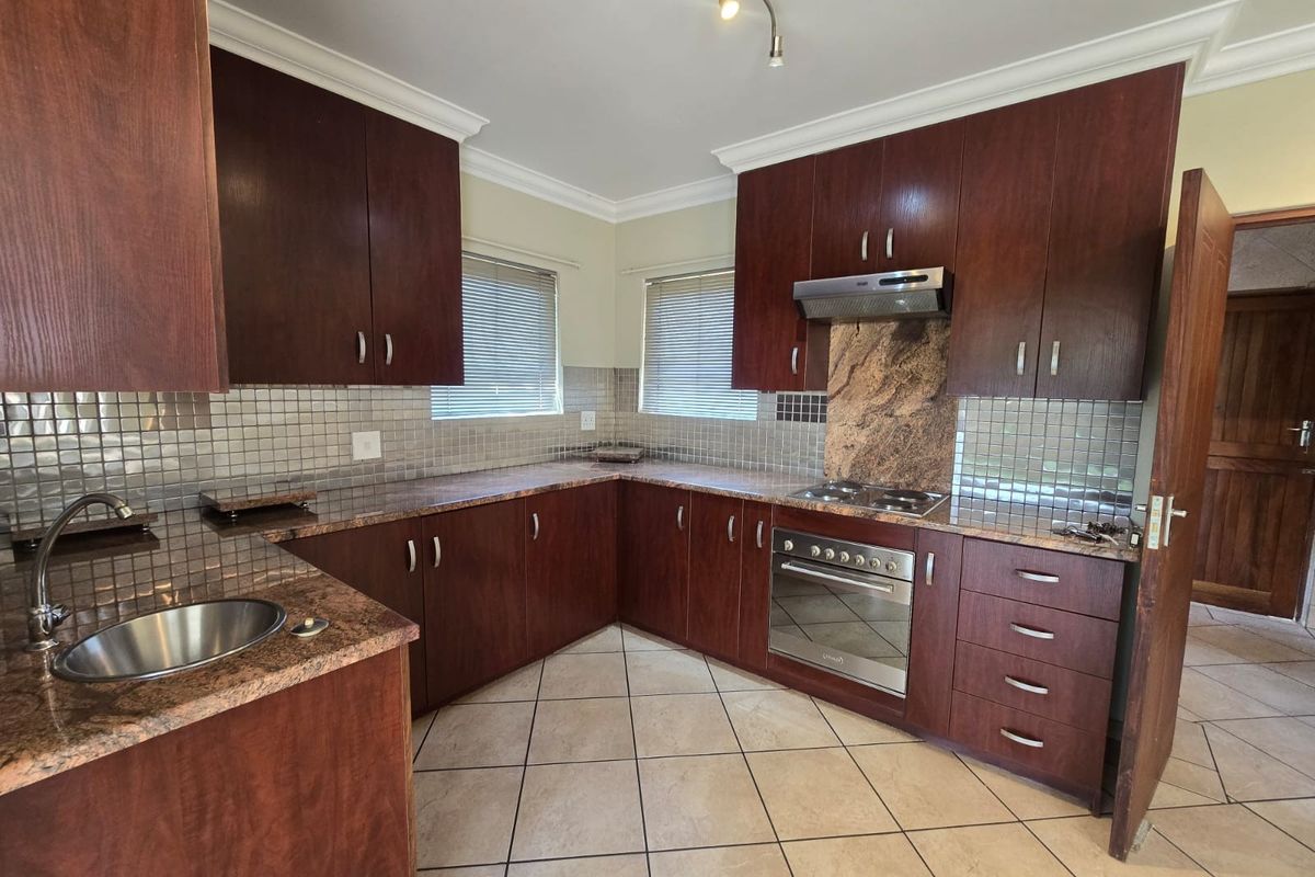 A functional kitchen featuring dark wood cabinetry, granite countertops, tiled backsplash, and built-in stainless steel appliances, offering a clean and practical workspace.