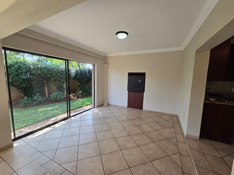 An empty living area featuring tiled flooring, cove ceiling molding, and a large sliding glass door providing direct access to the garden.