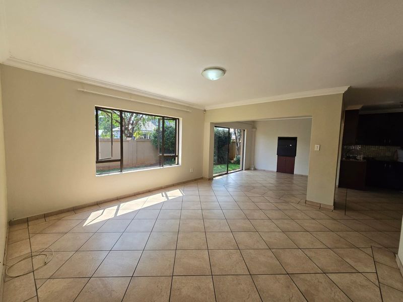 Spacious open-plan living area featuring neutral tiled flooring, large windows for natural light, and a built-in fireplace, offering a versatile layout.
