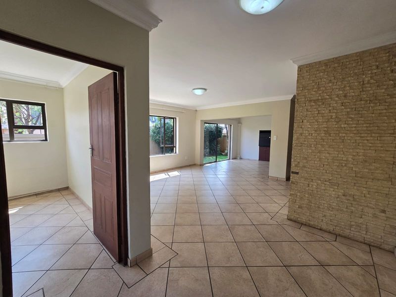 Spacious open-plan living area featuring neutral ceramic floor tiles, a decorative stone-clad feature wall, and large sliding doors providing access to the garden.