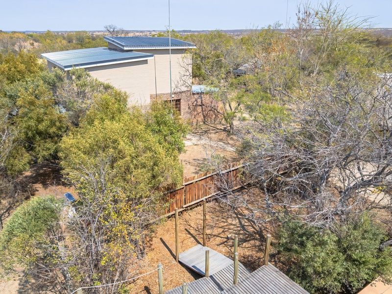 Aerial view of the farm property featuring a modern structure with a metal roof, timber decking, and surrounding natural landscape.
