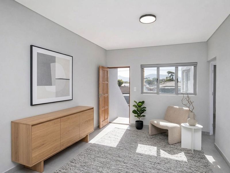 A bright and modern living area featuring neutral tiled flooring, clean wall finishes, and natural light through aluminium-framed windows with direct outdoor access.
