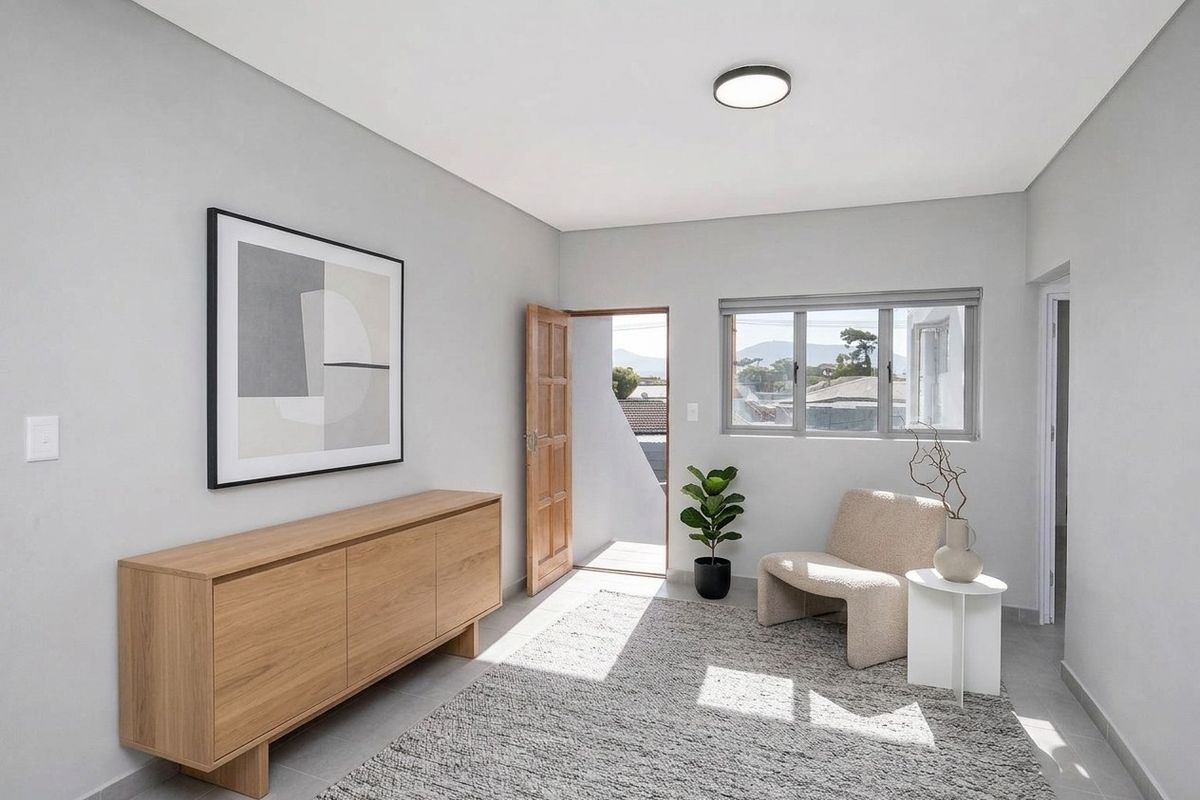A bright and modern living area featuring neutral tiled flooring, clean wall finishes, and natural light through aluminium-framed windows with direct outdoor access.