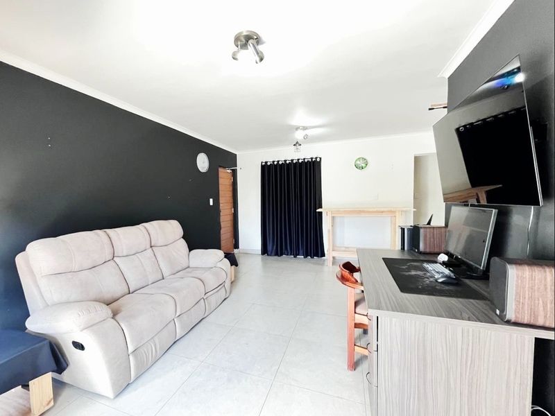 A living room featuring neutral tiled flooring and a contrasting black accent wall, providing a functional and open space for relaxation.