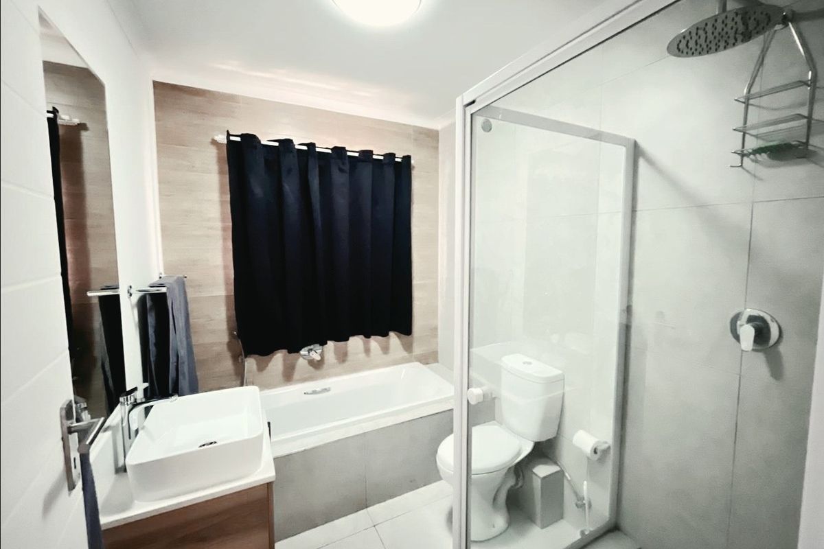 Modern bathroom featuring a vanity with vessel sink, a separate bathtub, and a glass-enclosed shower with rainfall shower head.