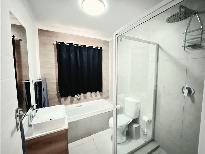 Modern bathroom featuring a vanity with vessel sink, a separate bathtub, and a glass-enclosed shower with rainfall shower head.