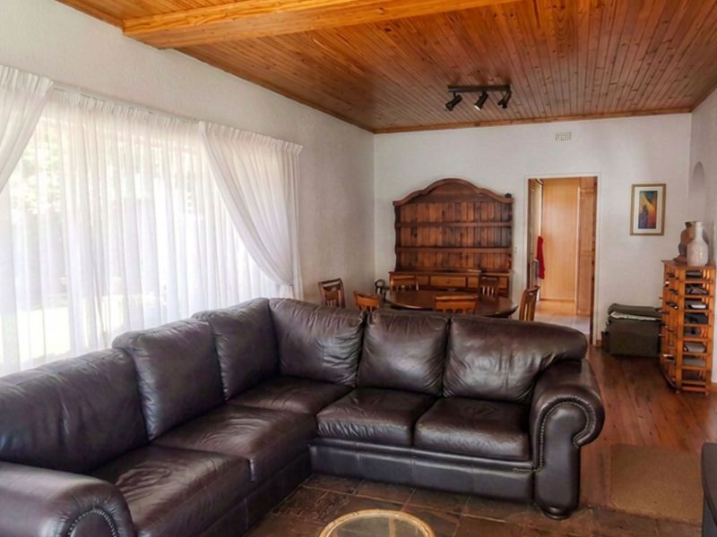 Spacious living area featuring a warm timber-clad ceiling, stone tile flooring, and an inviting archway leading to adjacent rooms.