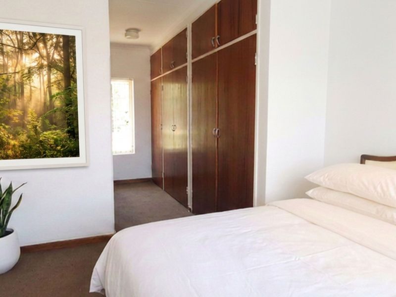 A bedroom featuring built-in wooden cupboards and carpeted flooring, offering a clean and functional space.