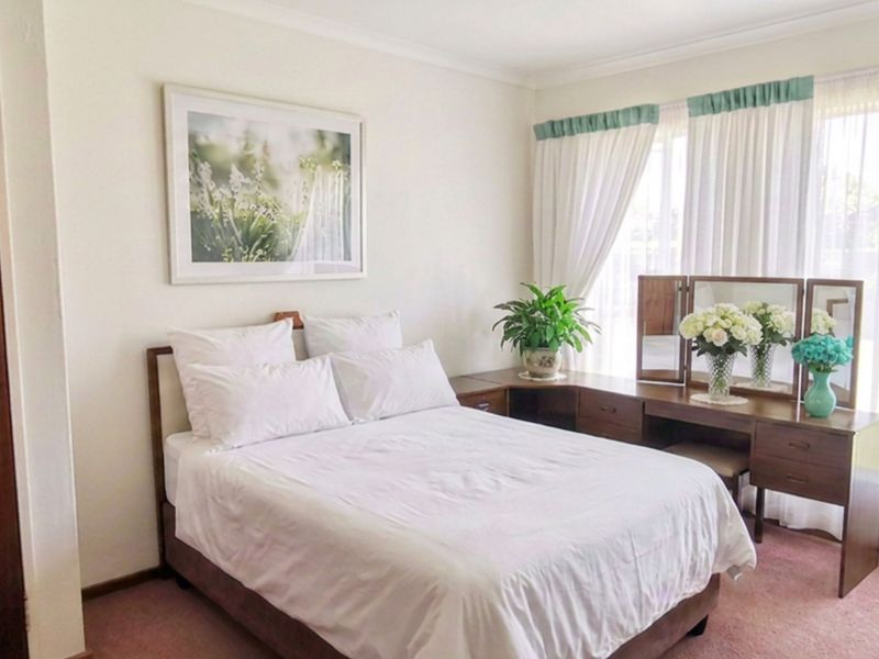 A well-lit bedroom featuring carpeted flooring, a built-in wardrobe, and a sliding glass door providing access to the exterior.