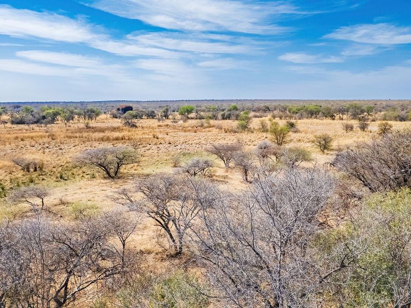 An aerial view of a large, undeveloped residential land plot featuring natural savanna-style vegetation and open terrain.
