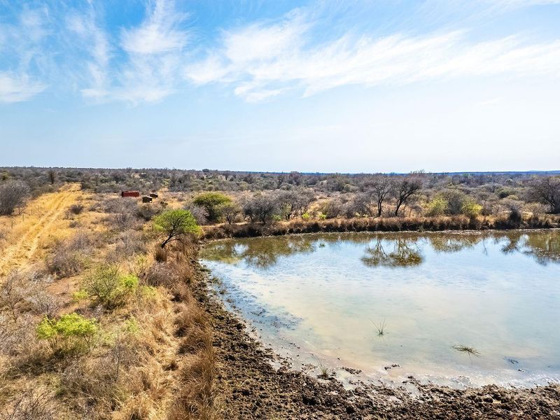 Aerial view of vacant residential land featuring a natural dam and an existing dirt track access road.