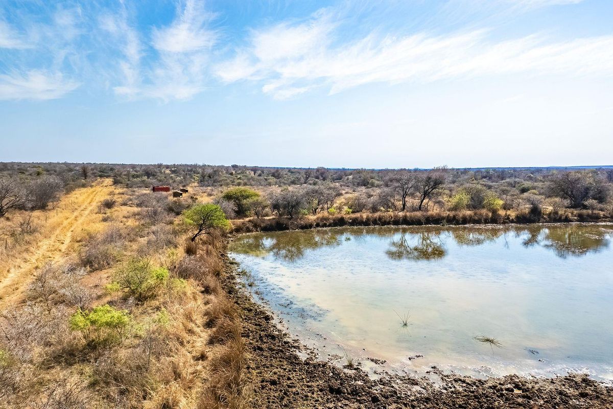 Aerial view of vacant residential land featuring a natural dam and an existing dirt track access road.