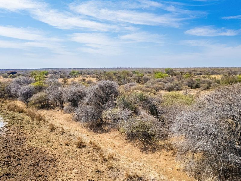 An aerial view of the vacant residential land featuring natural bushveld vegetation and a small water source.