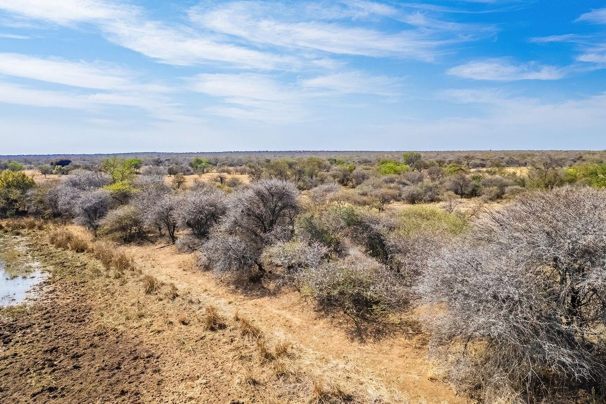 An aerial view of the vacant residential land featuring natural bushveld vegetation and a small water source.