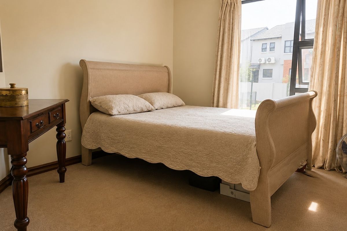 A well-lit bedroom featuring neutral carpeted flooring and a large window that allows for ample natural light.