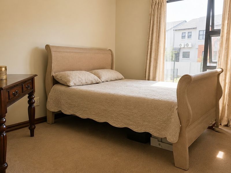 A well-lit bedroom featuring neutral carpeted flooring and a large window that allows for ample natural light.