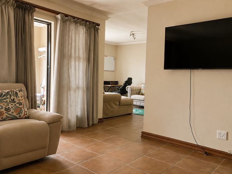 A well-maintained living area featuring tiled flooring, coving, and a sliding glass door providing access to an outdoor space.