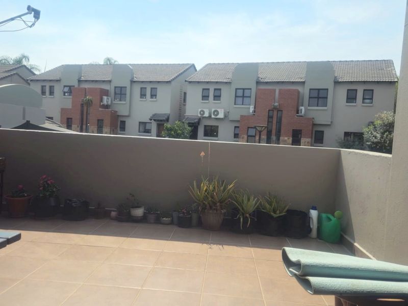 A spacious open-air balcony featuring tiled flooring and a solid plastered masonry perimeter wall, offering a clear view of the surrounding residential complex.