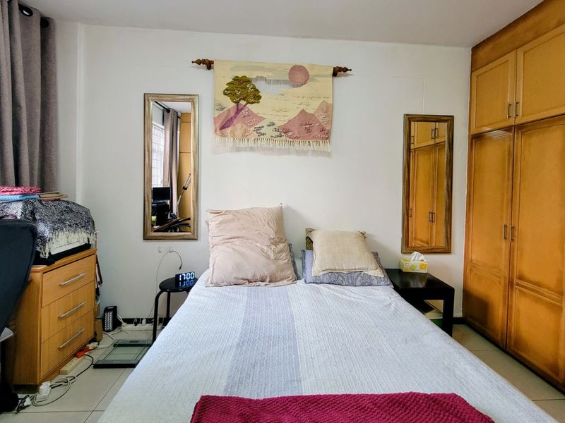 A bedroom featuring built-in wooden wardrobes and tiled flooring, offering functional storage space.