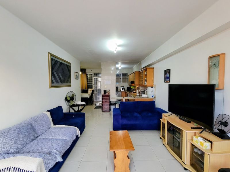 Open plan living area featuring tiled flooring and a functional kitchen space with built-in cabinetry and countertops.