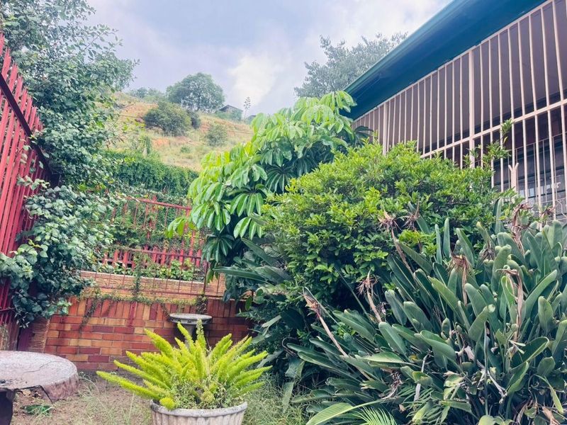 A private garden area featuring established greenery, brick retaining walls, and metal security screening along the side of the property.