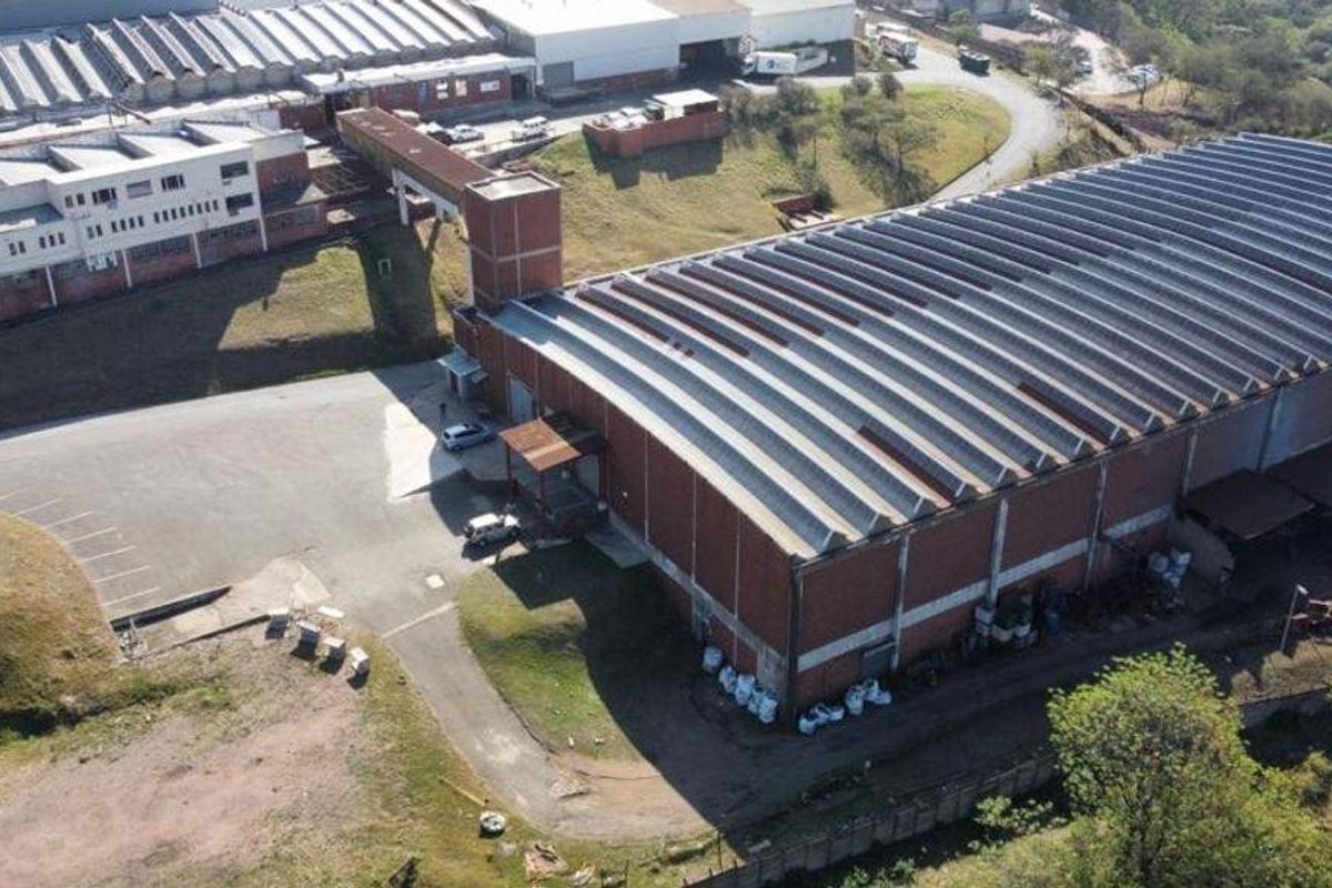 Aerial view of a large industrial warehouse complex featuring corrugated roofing, brick construction, and an expansive paved yard area.