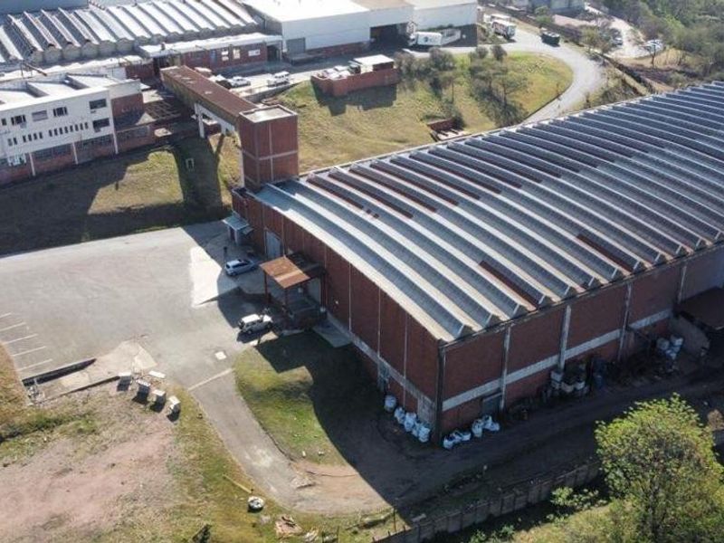 Aerial view of a large industrial warehouse complex featuring corrugated roofing, brick construction, and an expansive paved yard area.