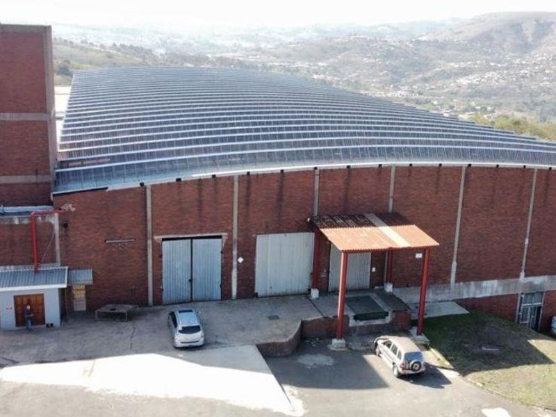 Aerial view of a large industrial warehouse facility featuring a brick exterior, solar panel roof, and dedicated loading bay infrastructure.