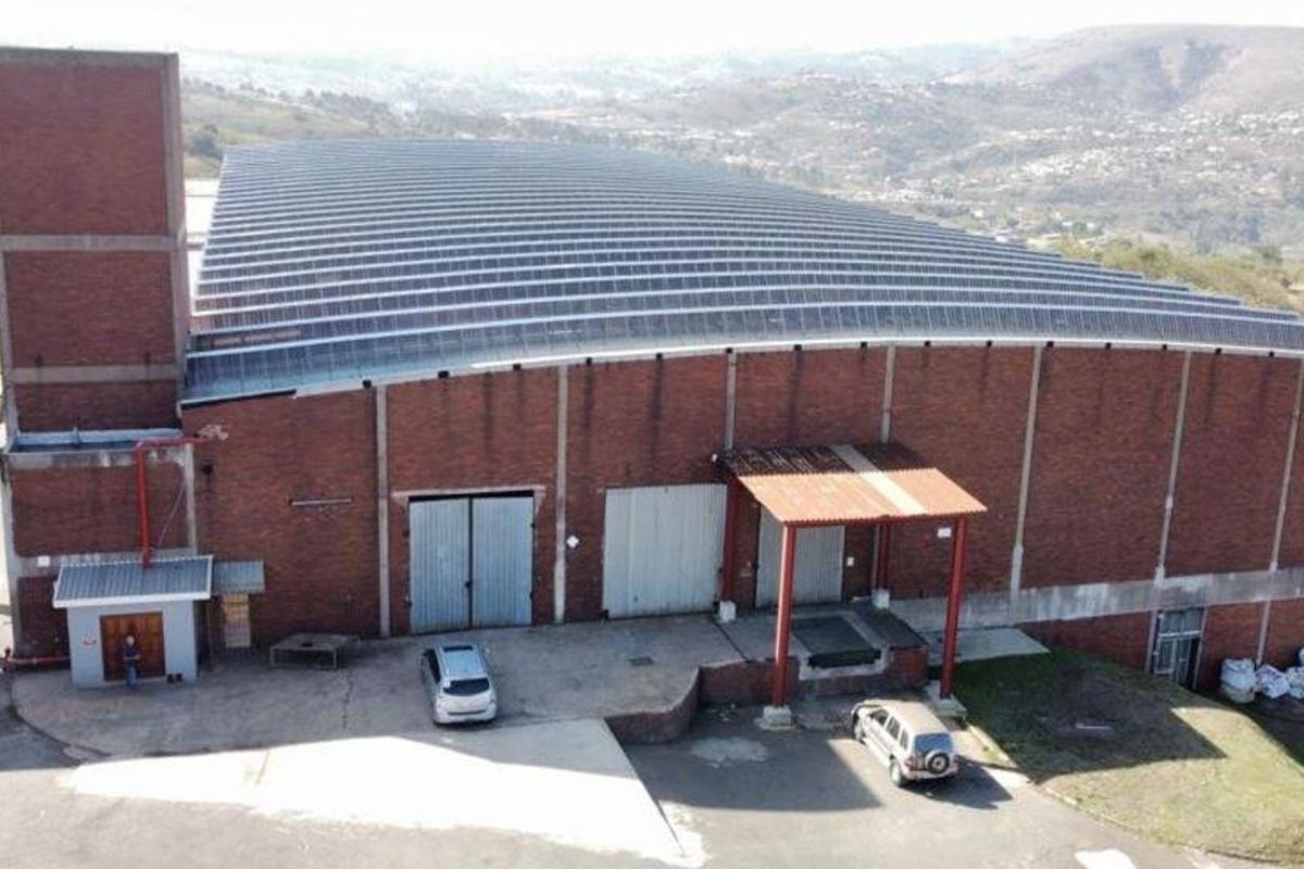 Aerial view of a large industrial warehouse facility featuring a brick exterior, solar panel roof, and dedicated loading bay infrastructure.