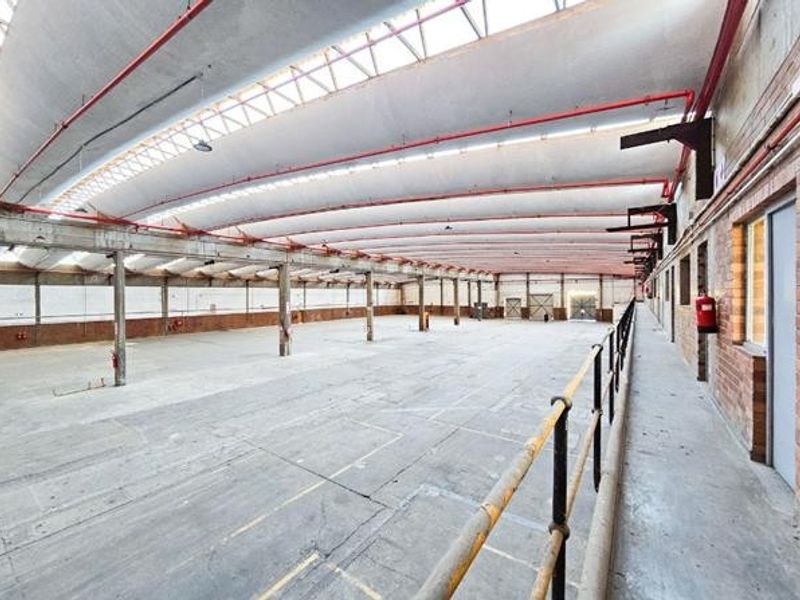 Expansive industrial warehouse space featuring high vaulted ceilings with skylights, concrete flooring, and integrated fire safety systems.