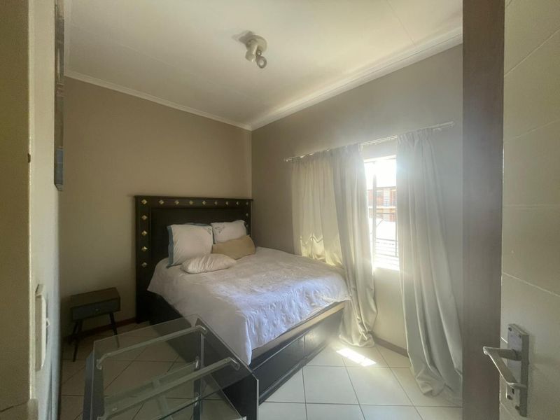A bedroom featuring tiled flooring and a window with natural light, providing a functional space for rest.