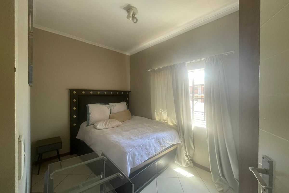 A bedroom featuring tiled flooring and a window with natural light, providing a functional space for rest.