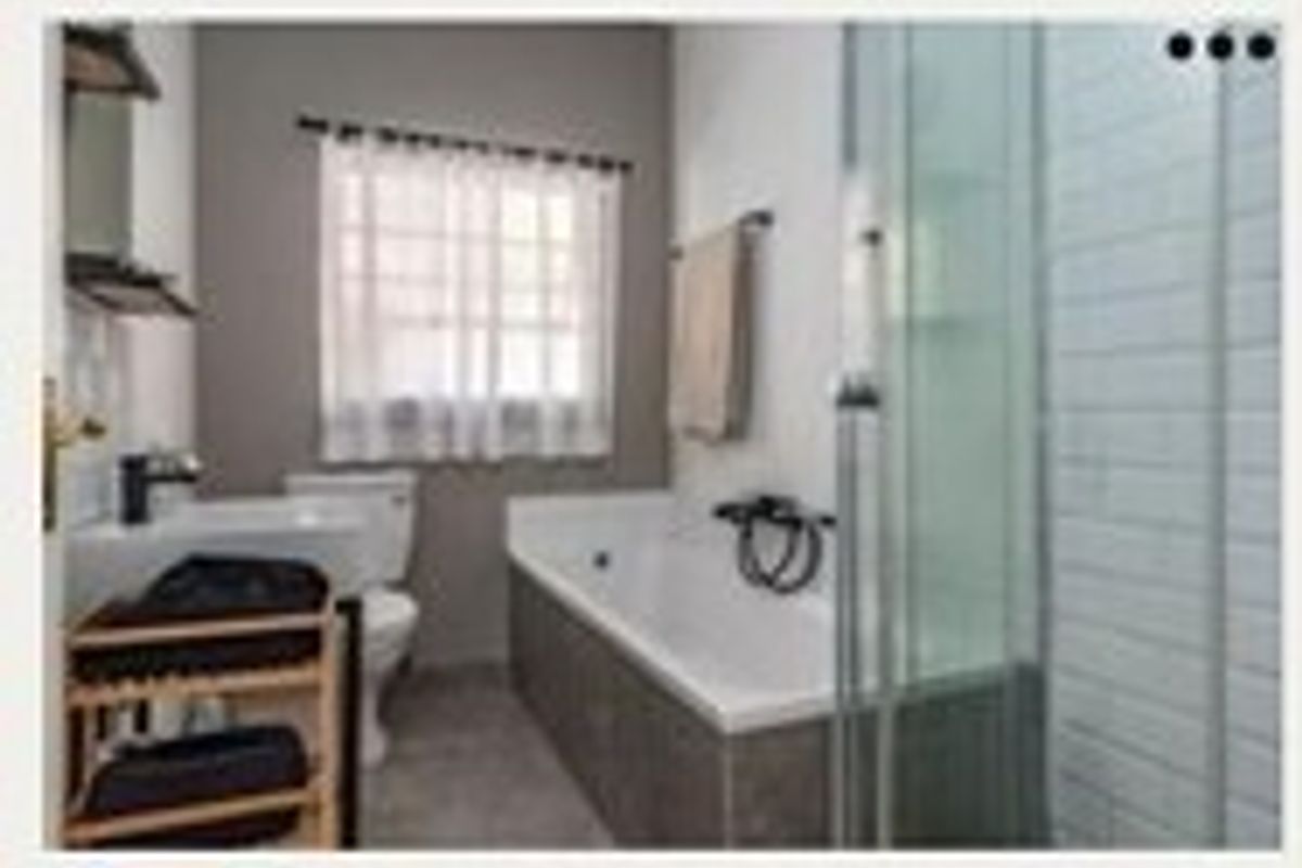 A functional bathroom featuring a bathtub, separate shower enclosure, basin, and toilet with modern tiled finishes.