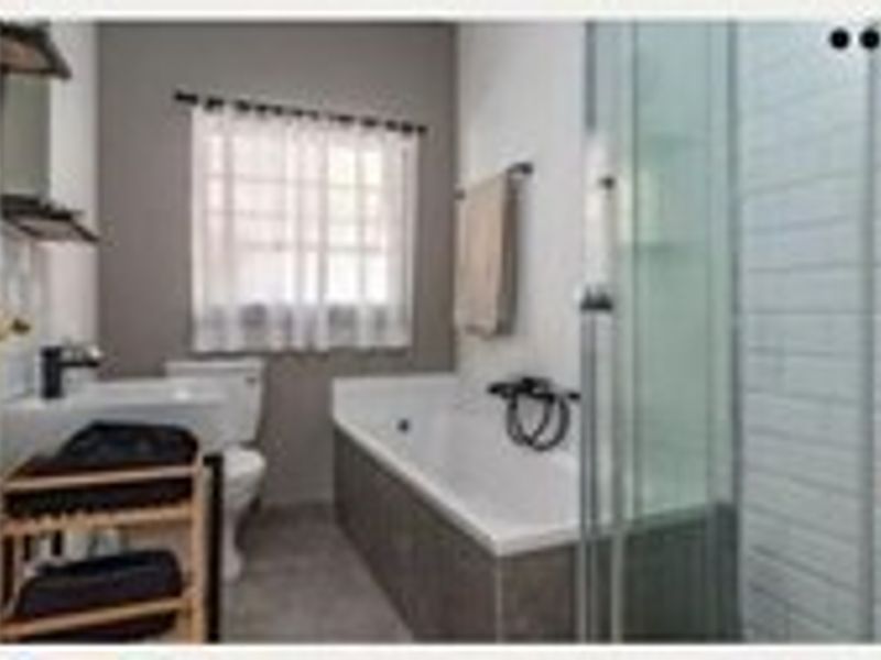 A functional bathroom featuring a bathtub, separate shower enclosure, basin, and toilet with modern tiled finishes.