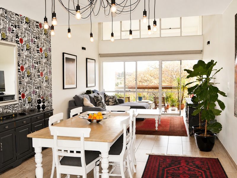 Spacious open-plan living and dining area featuring tiled floors, high ceilings with transom windows, and large sliding doors leading to a balcony.