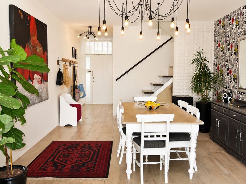 Open-plan dining area featuring tiled flooring, a textured feature wall, and a modern staircase leading to the upper level.