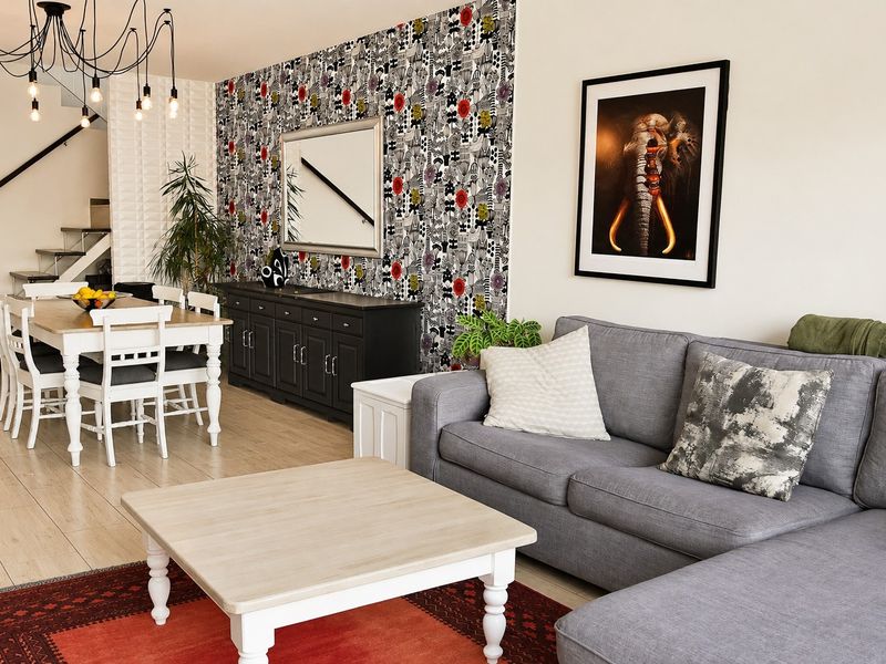 Open-plan living and dining area featuring modern pendant lighting, textured wall accents, and tiled flooring with an integrated staircase.