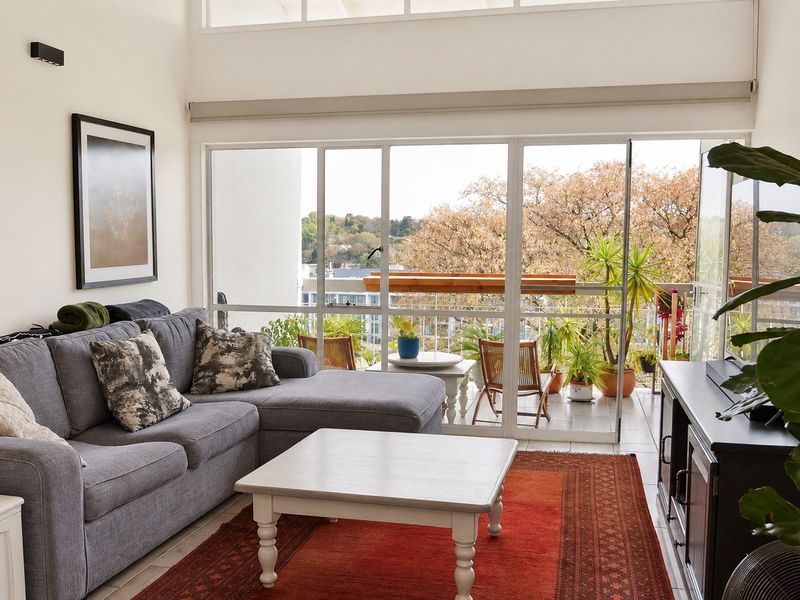 Bright living room featuring high ceilings, clerestory windows, and large sliding glass doors that open onto a private balcony with scenic views.