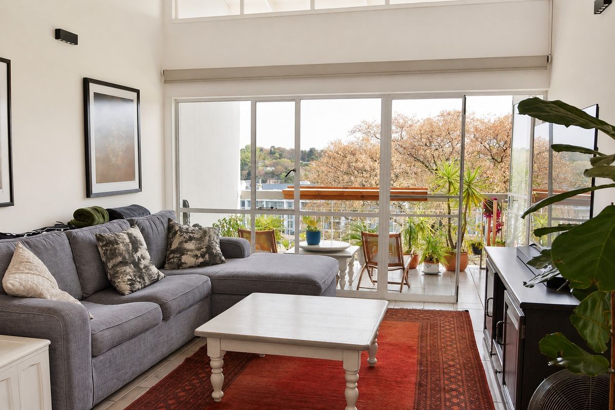 Bright living room featuring high ceilings, clerestory windows, and large sliding glass doors that open onto a private balcony with scenic views.