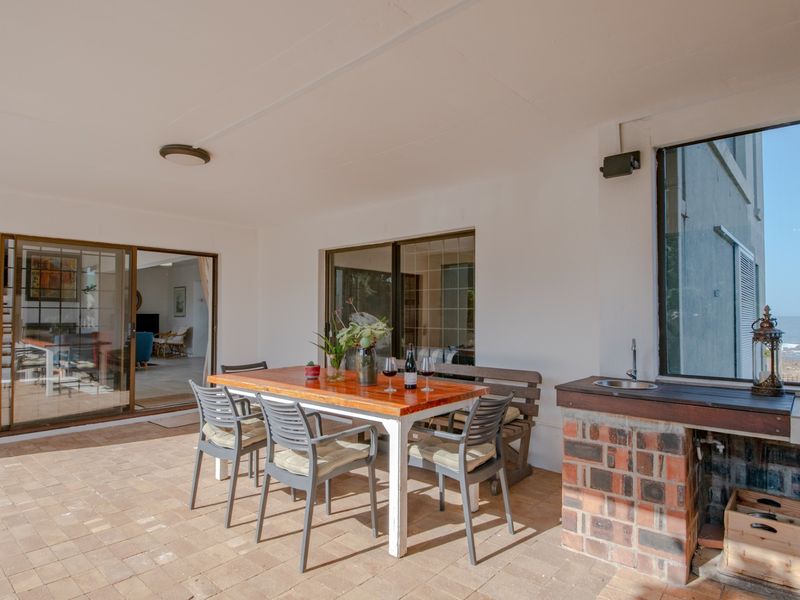 Covered patio featuring a brick built-in braai with sink, paved flooring, and sliding glass doors providing seamless access to the interior living space.
