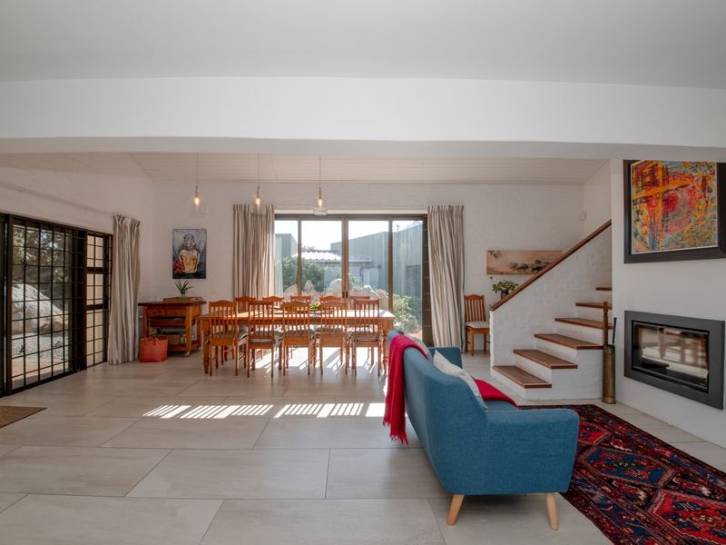 Spacious open-plan living and dining area featuring large format floor tiles, a built-in fireplace, and direct access to the outdoor patio through sliding doors.