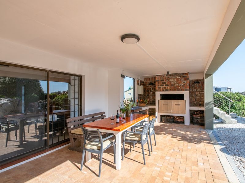 Covered outdoor patio featuring brick paving and a built-in braai area, providing a functional space for outdoor dining and entertainment.