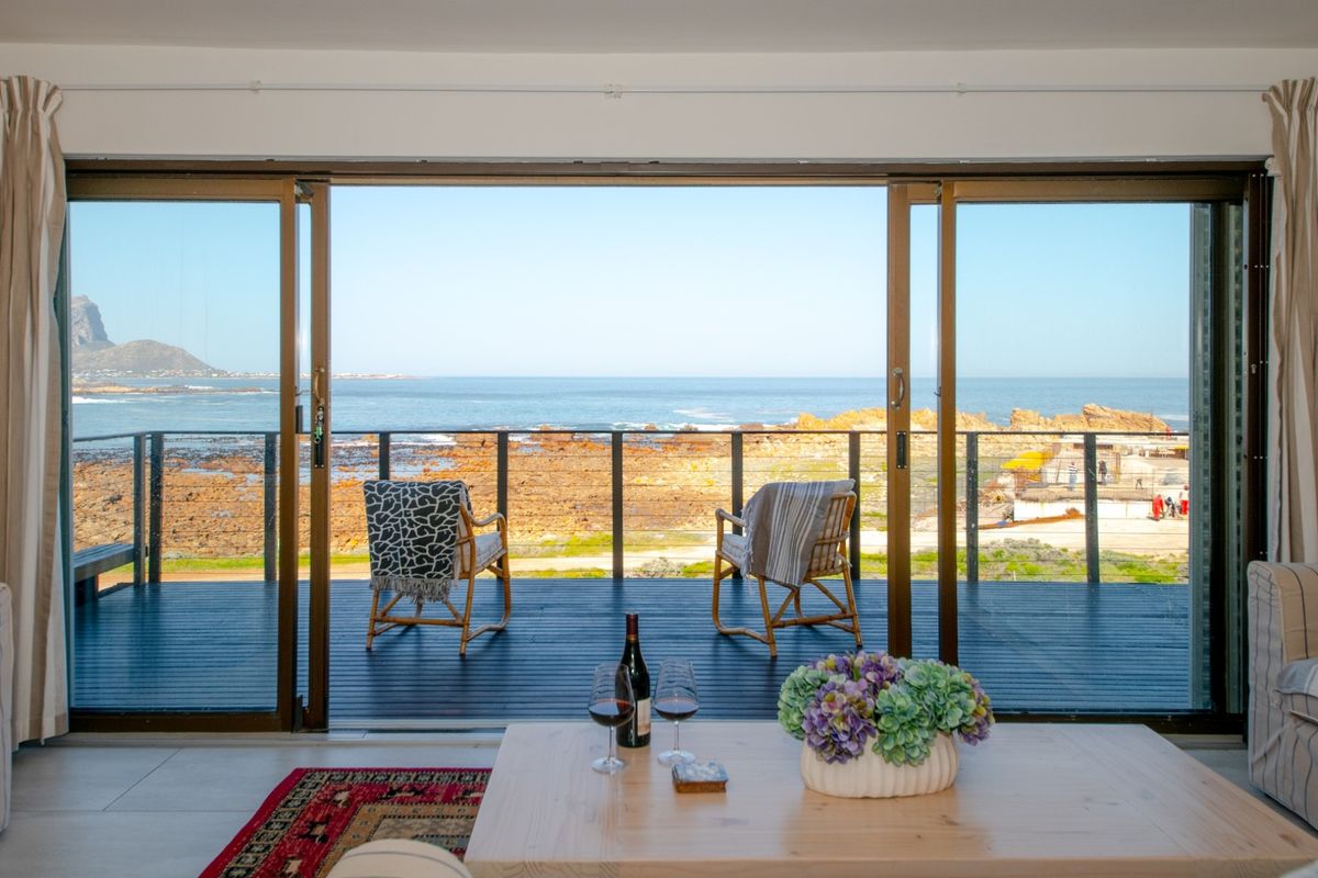 Living room featuring large sliding glass doors opening onto a deck with expansive ocean views.