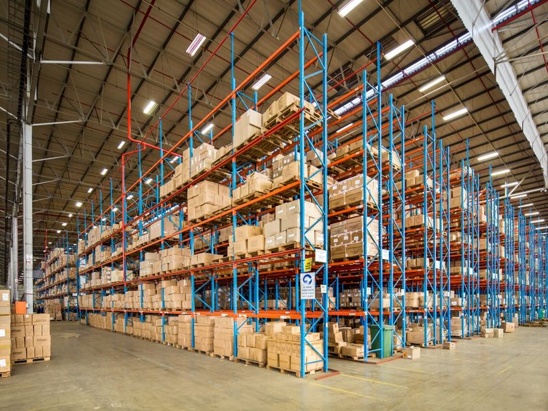 Large industrial warehouse space featuring extensive high-bay racking systems, exposed steel roof structure, and durable concrete flooring suitable for logistics or storage operations.