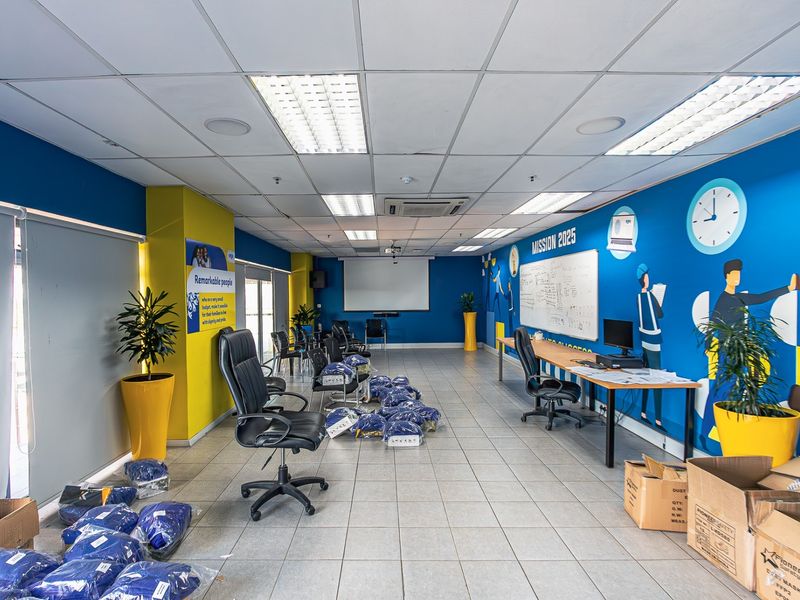Spacious industrial office area featuring tiled flooring, suspended ceiling with recessed lighting, integrated air conditioning, and a large wall-mounted whiteboard.